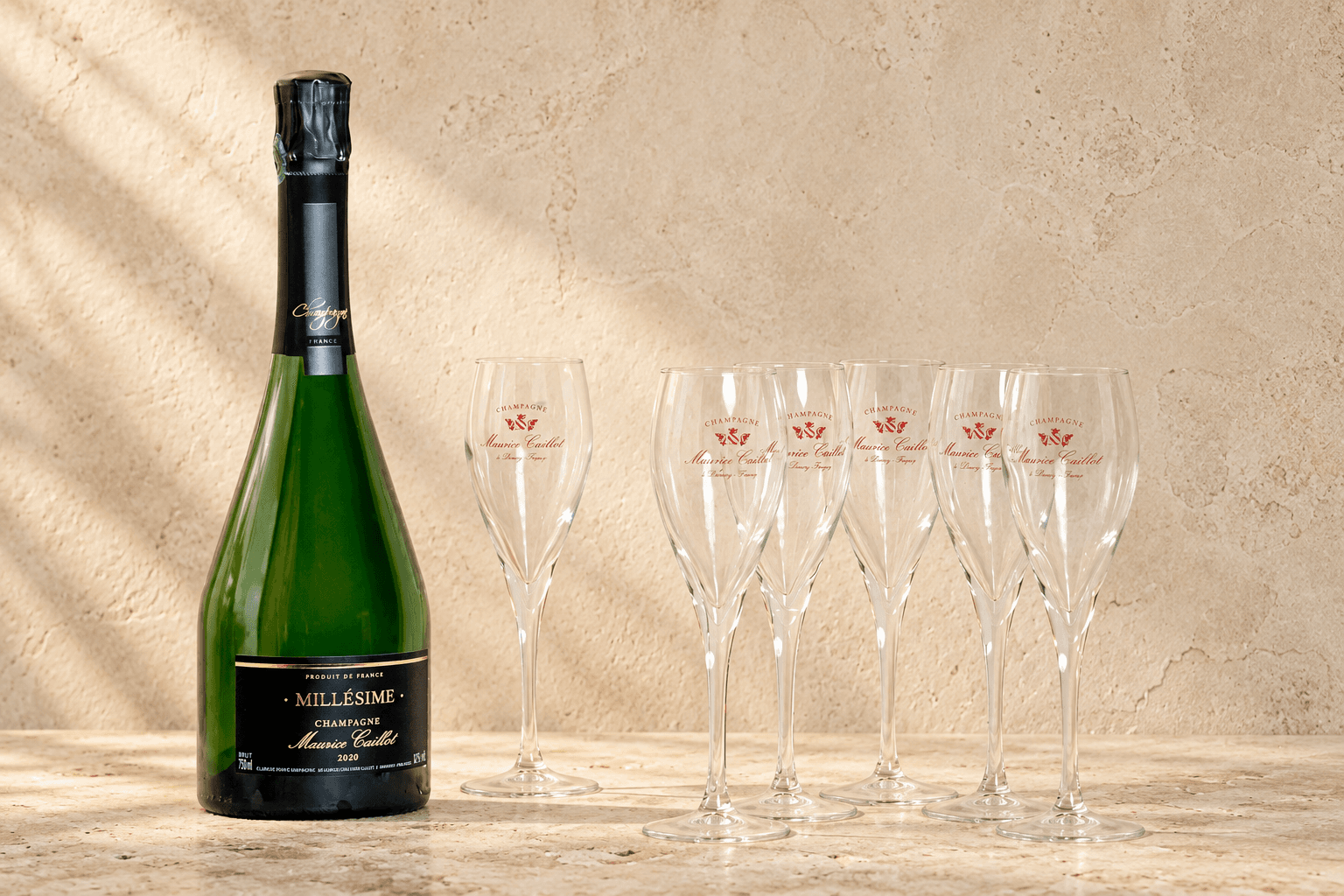Champagne Millésime et flûtes Maurice Caillot sur une pierre claire